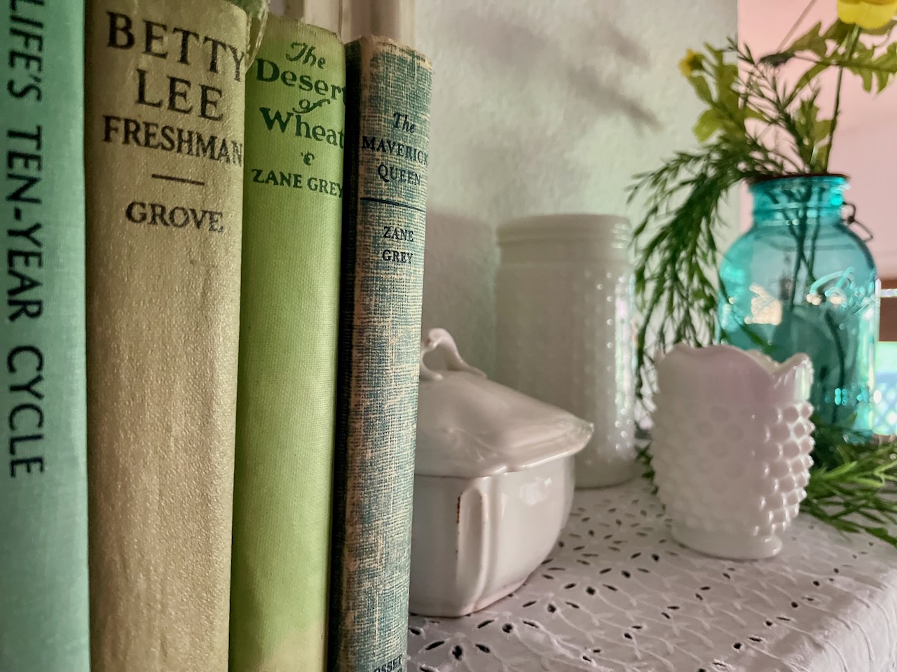 vintage books with milk glass on a shelf for Summer
