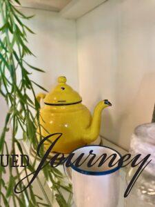 a green stem with a vintage yellow enamel teapot