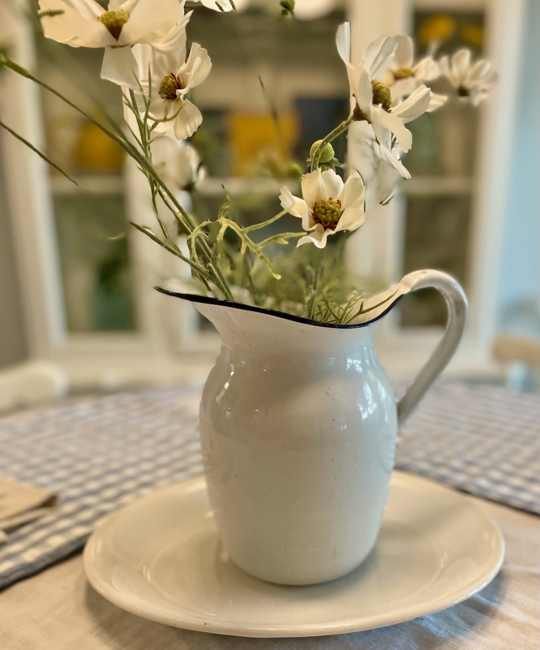 a vintage ironstone platter with an enamel pitcher on a table