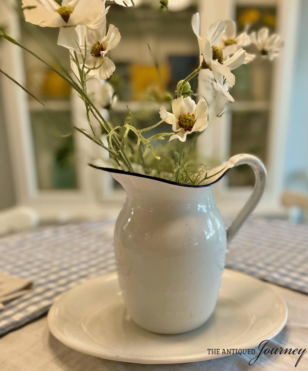 a vintage ironstone platter with an enamel pitcher on a table
