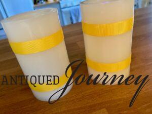 two faux pillar candles wrapped with gold ribbon