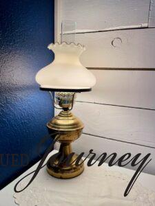 a vintage brass lamp sitting on a vintage white linen