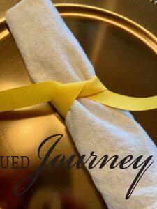 a linen napkin tied with a gold ribbon for a Sunflower tablescape