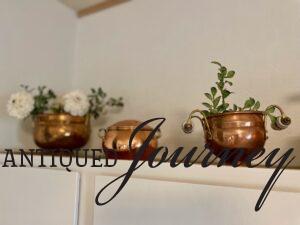 faux greenery and white flowers displayed in vintage copper