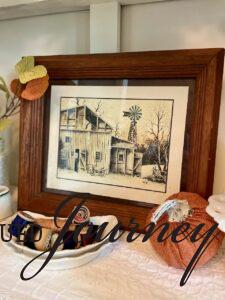 a vintage barn print with a wood frame styled in a hutch for Fall