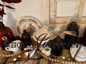 vintage plates and amber bottles used in a Fall display