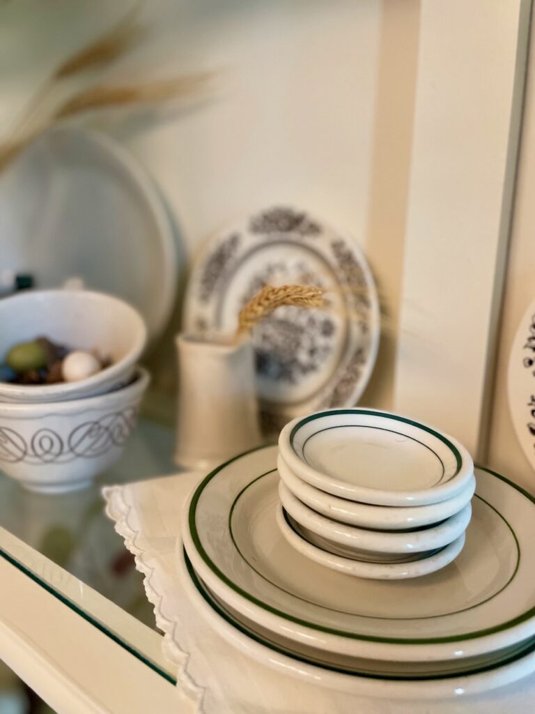 vintage butter pats and plates styled into a hutch for Fall