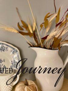 a vintage enamel pitcher with Fall faux stems in a bathroom