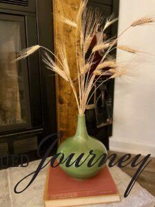 faux wheat stems in a vintage green vase on a hearth