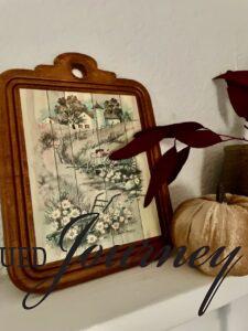 thrifted country artwork on a shelf in an entry for Fall decor