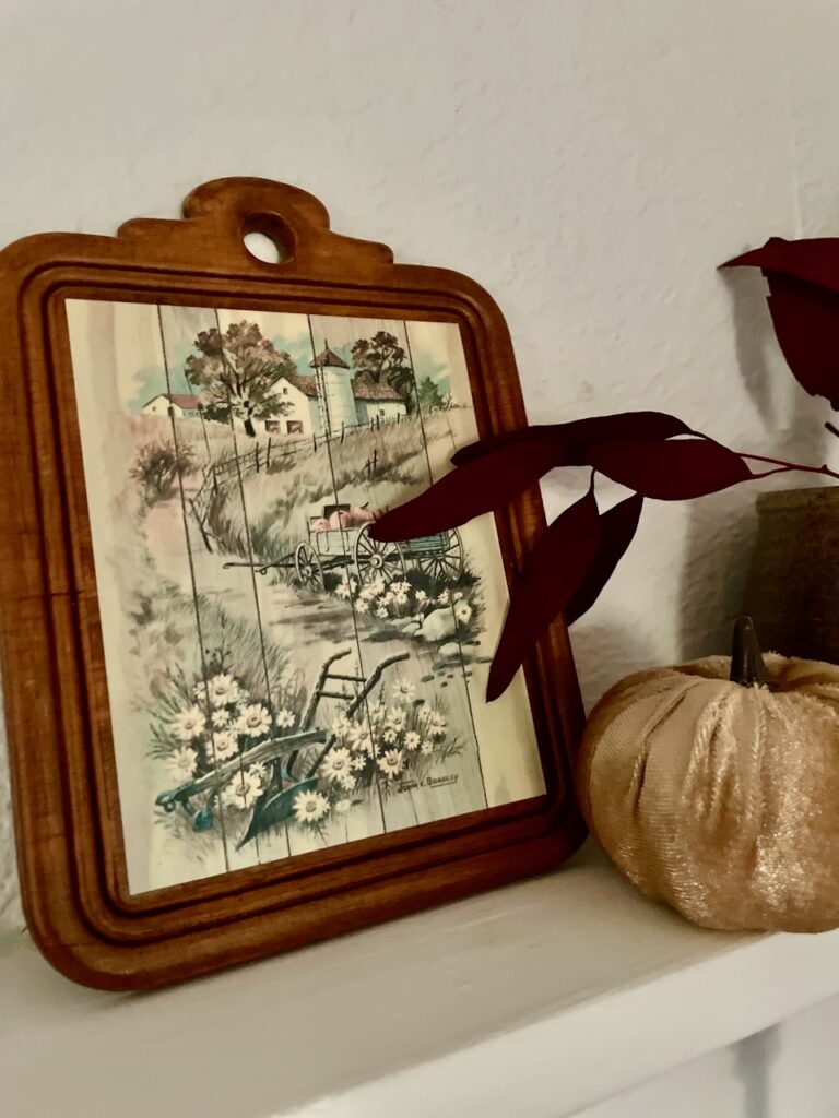 a thrifted Fall wood plaque displayed with a pumpkin