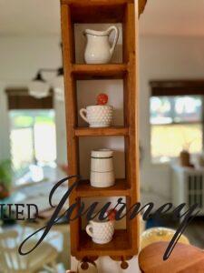 a thrifted wooden cubby shelf styled with vintage cafe creamers in a kitchen