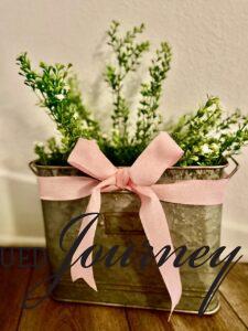 a pink ribbon tied around a floral display