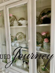 a white hutch styled for Spring with vintage dishes