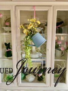 full watering can wreath on a hutch door